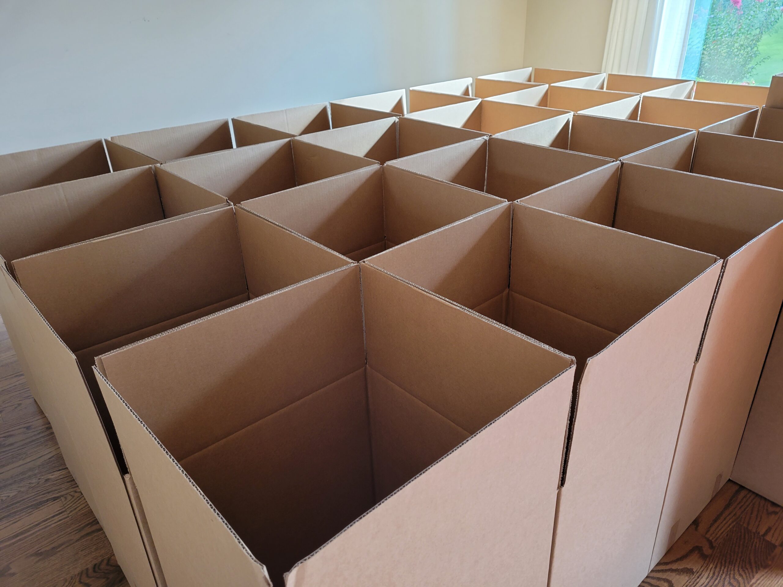 Cardboard moving boxes arranged in a spacious room, illustrating essential packing supplies for a stress-free move.