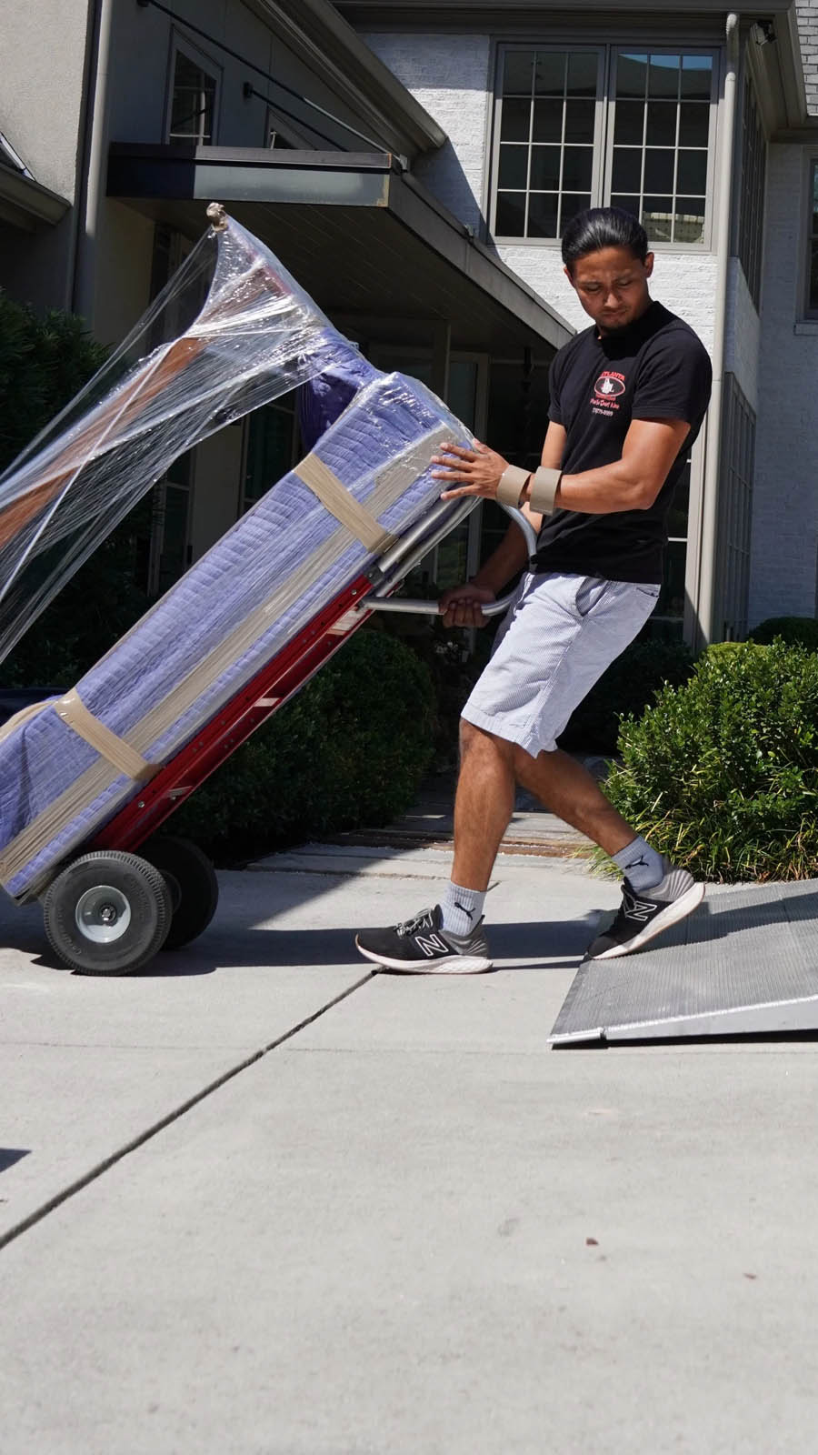 Mover transporting a securely wrapped couch on a dolly, showcasing professional moving services in a residential setting, emphasizing care and efficiency for long-distance relocations.