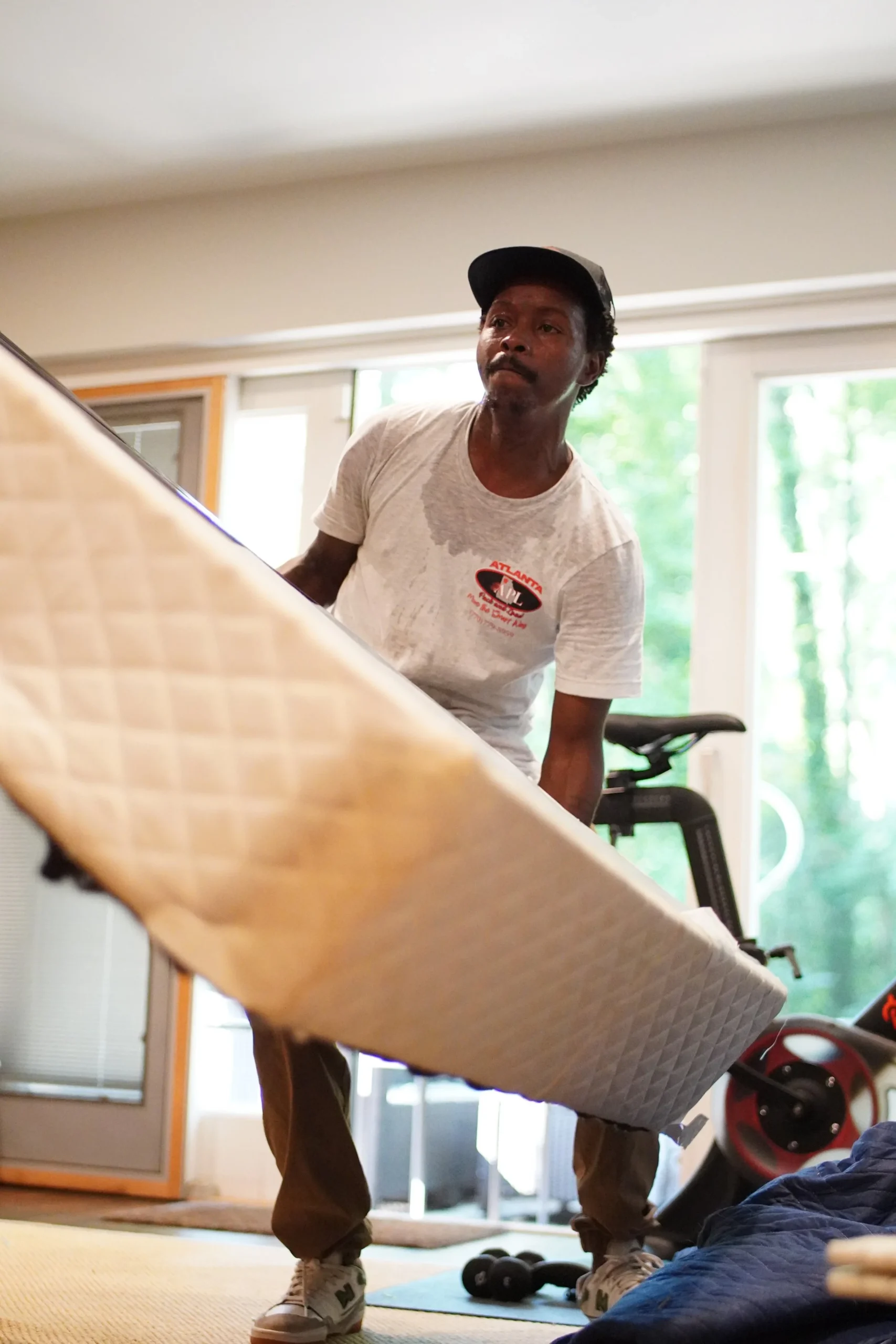 Man lifting a mattress indoors, showcasing donation and disposal services by Atlanta Pack & Load in Austell, GA, emphasizing clutter removal and stress-free moving.