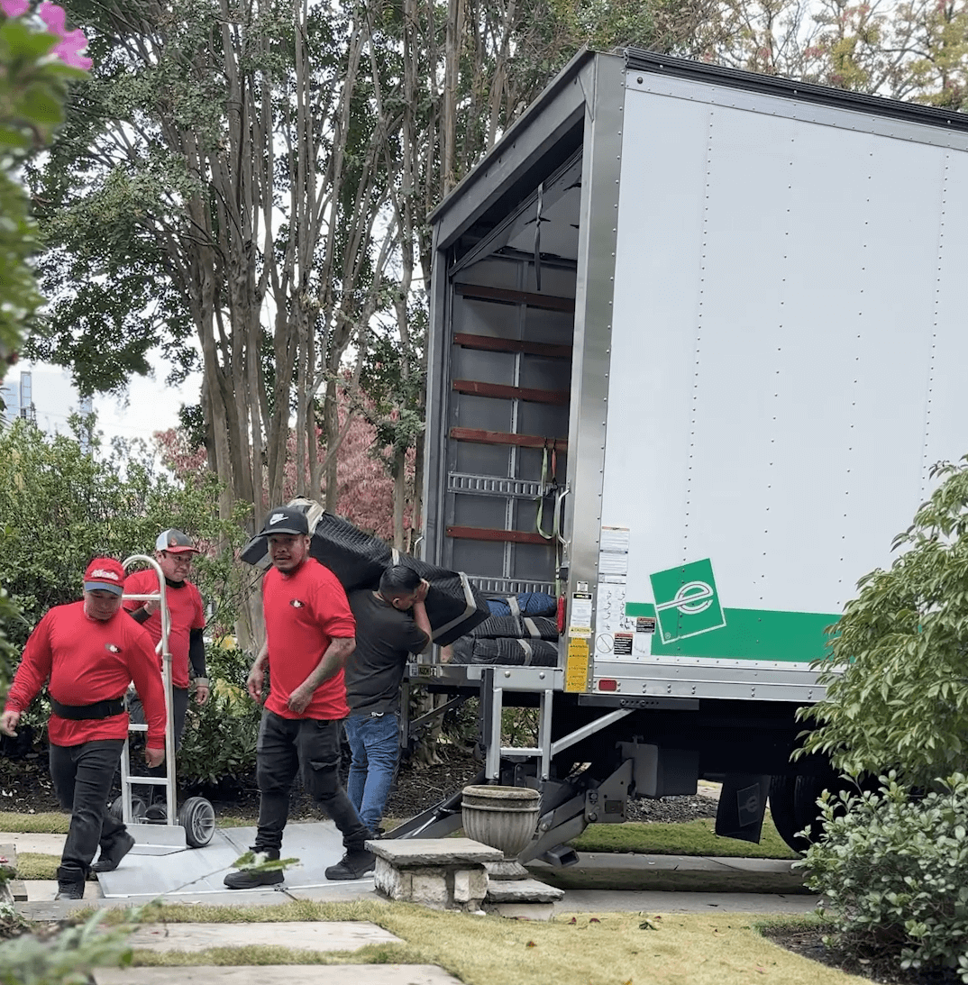 Moving team in red shirts loading furniture into a moving truck, showcasing professional moving services in Austell, GA.