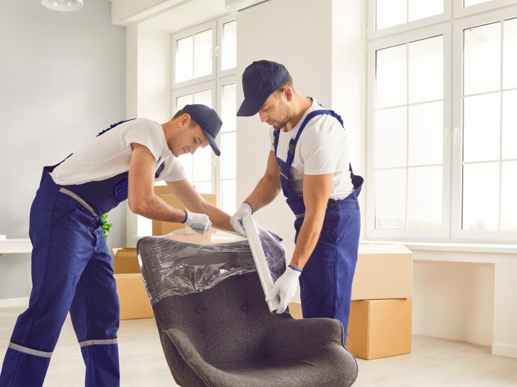 Movers carefully wrapping a chair in protective material during a long-distance move, emphasizing the importance of safeguarding valuables in transit.