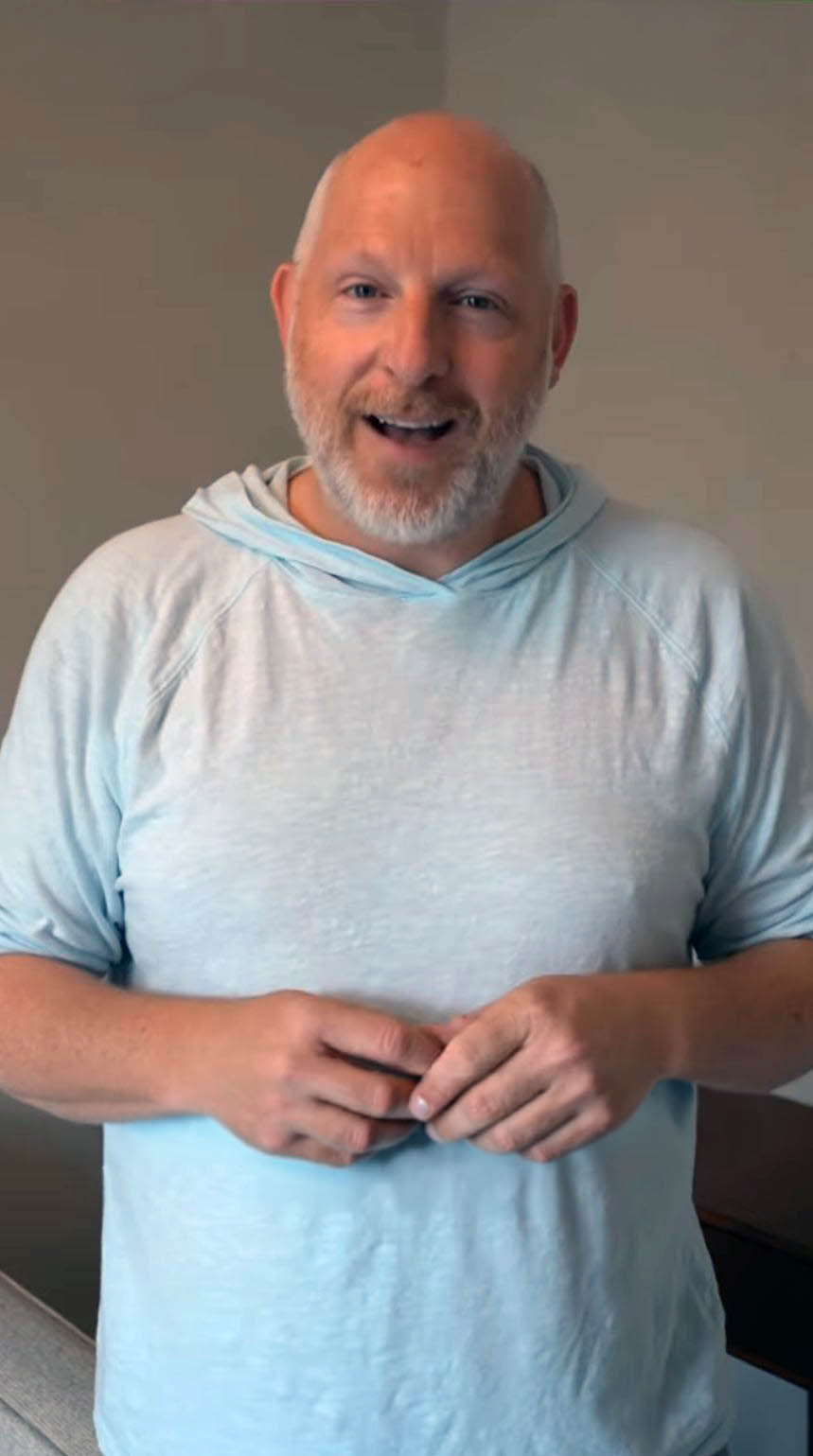 Smiling man in a light blue hoodie discussing moving services, representing customer satisfaction with Atlanta Pack and Load.