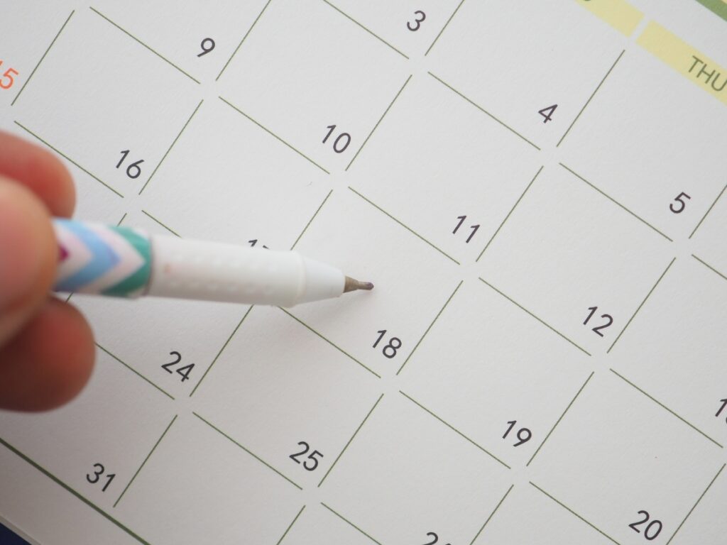 A hand holding a pen points to the 18th day on a calendar page with numbered squares, highlighting an upcoming Utility Disconnection.