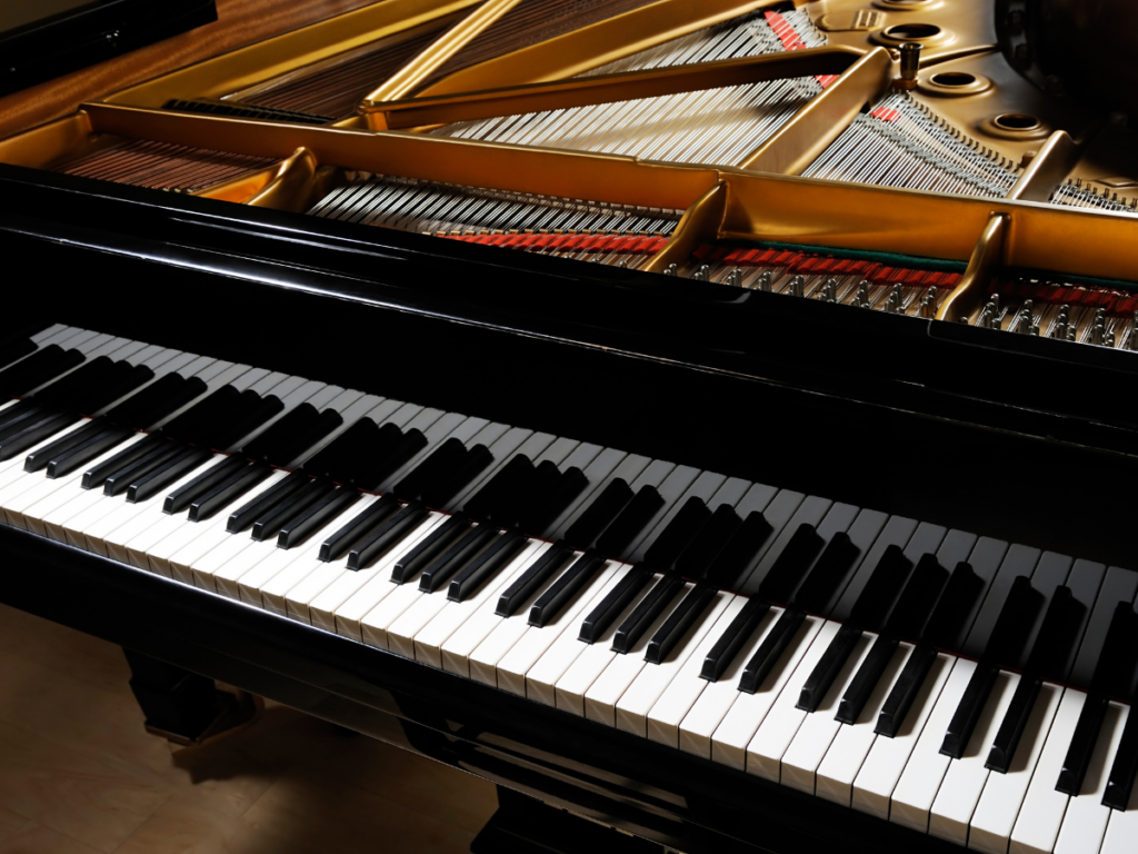 Close-up view of a grand piano keyboard and part of the open lid showing strings and internal components, ideal for showcasing special items moving with care during transport.