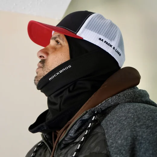 Man wearing a black neck gaiter and a cap with "GA PACK & LOAD" text, showcasing readiness for moving and storage services in a professional setting.